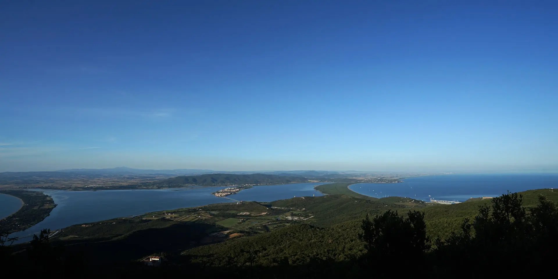 a view of a lake and mountains from a hill