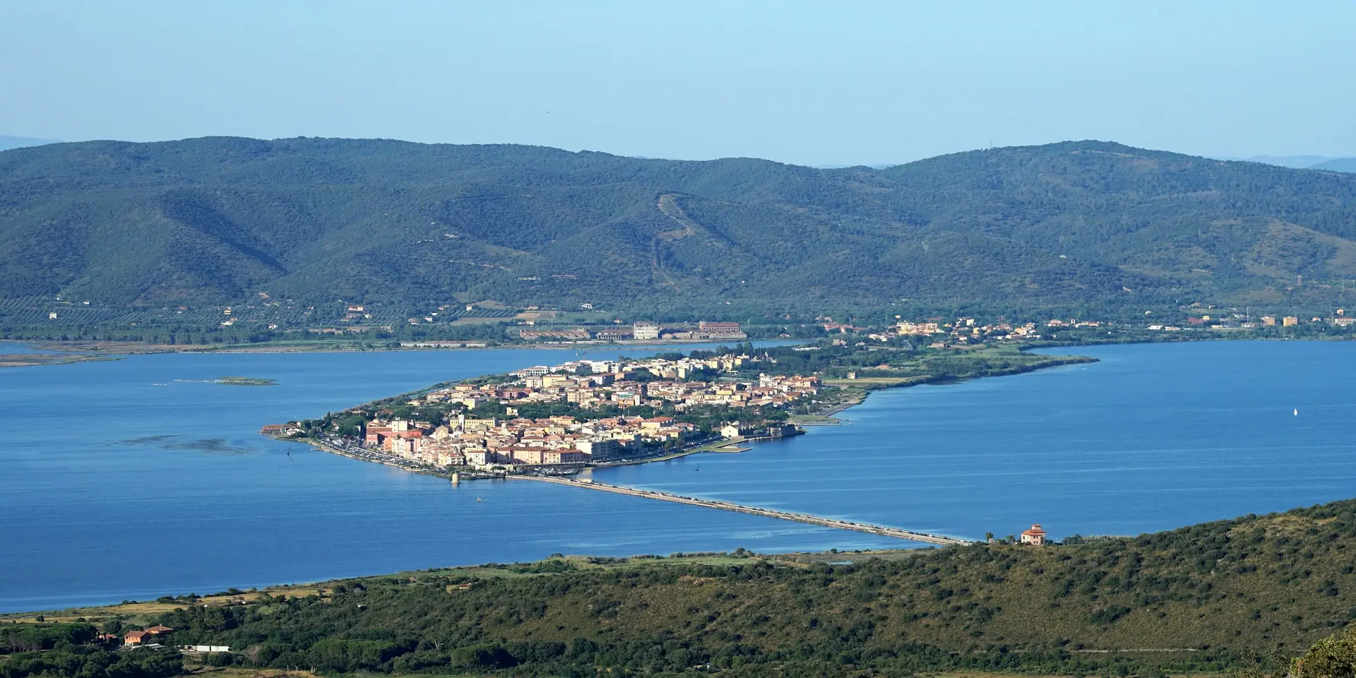 a view of a town and a body of water with mountains in the background